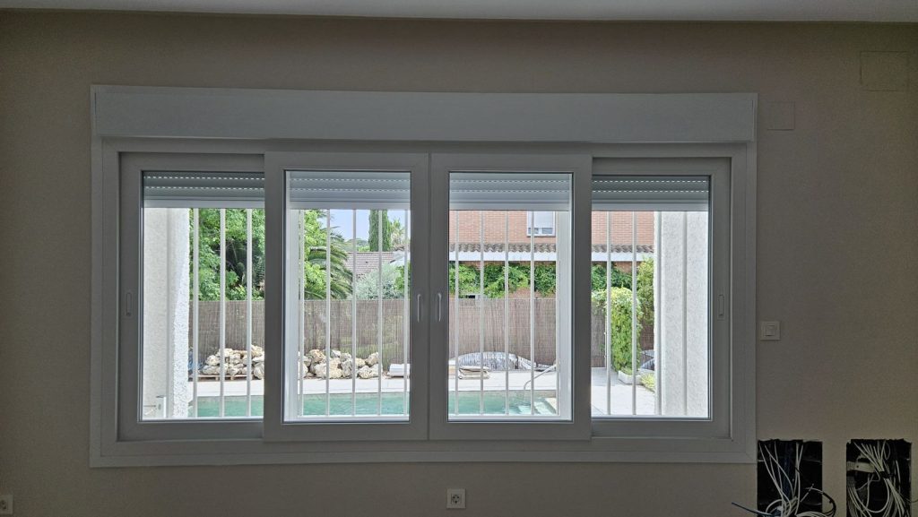 Ventana de PVC de cuatro hojas con persianas Ventana de PVC de cuatro hojas con persianas y vistas al jardín